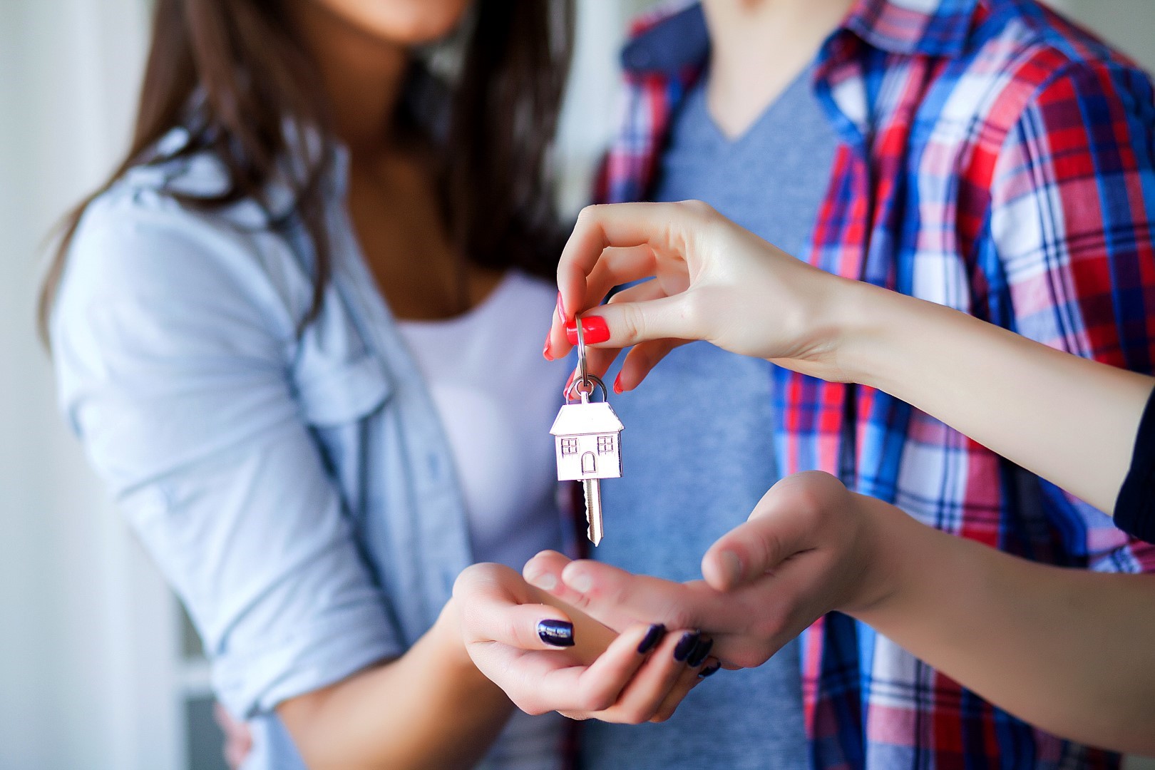 Casal rececebendo uma chave presa a um chaveiro em formato de casa